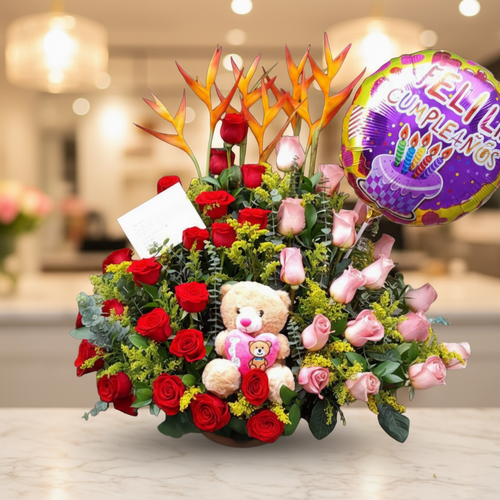 Arreglo floral de cumpleaños con globo y peluche Arreglo de flores con rosas rojas y rosas, flores exóticas naranjas, peluche de oso y globo de feliz cumpleaños sobre mesa en interior