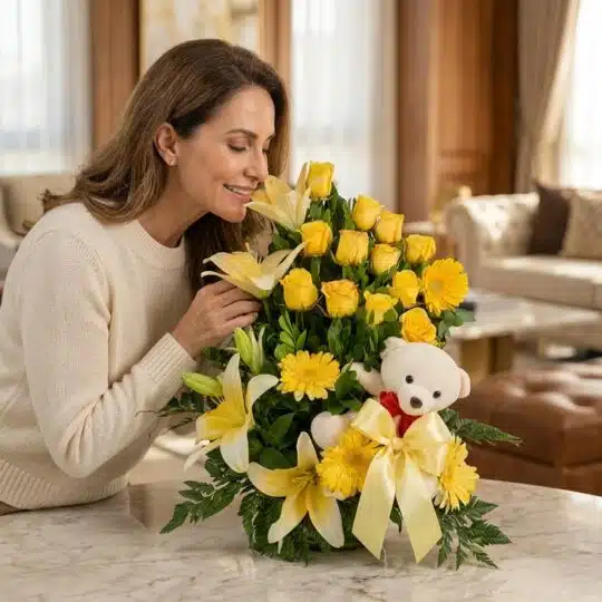 Mujer elegante admirando y oliendo un Arreglo Floral Exótico Amaretto con rosas amarillas, lirios y gerberas, acompañado de u