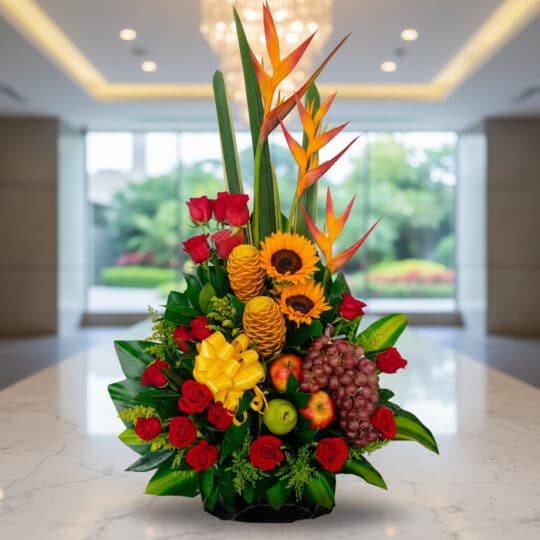 Arreglo floral premium con rosas rojas, girasoles, aves del paraíso, frutas durio, uvas y manzanas, sobre mármol en un lobby