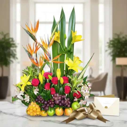 Arreglo floral Akebia con aves del paraíso, rosas rojas, lirios amarillos y frutas tropicales sobre mármol, listo para regalo