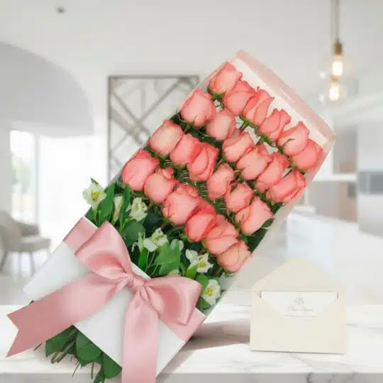 Caja de 24 rosas rosadas frescas con lazo de satén y tarjeta de regalo, sobre mármol en un ambiente elegante.
