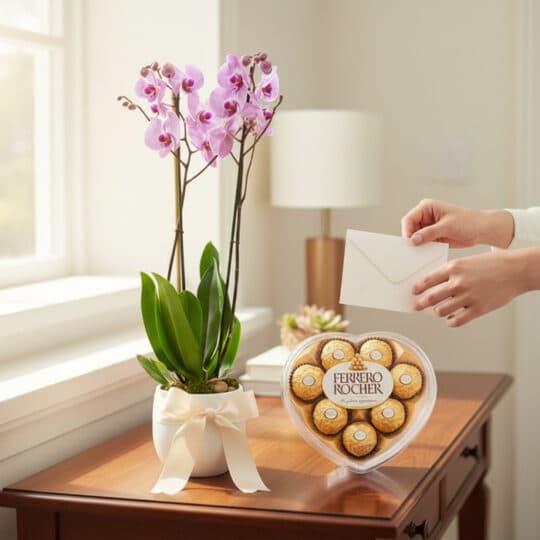 Arreglo premium Orquídea GALA con flores moradas y chocolates Ferrero Rocher en caja de corazón, sobre mesa de madera con man