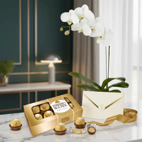 Arreglo MARELY con orquídea Phalaenopsis blanca, caja de chocolates Ferrero Rocher, tarjeta de regalo y cinta dorada sobre má