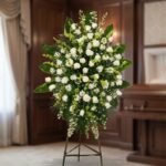 Pedestal fúnebre 'Nunca te Olvidaré' con rosas blancas, lirios y follaje verde, presentado en una sala de velación premium co